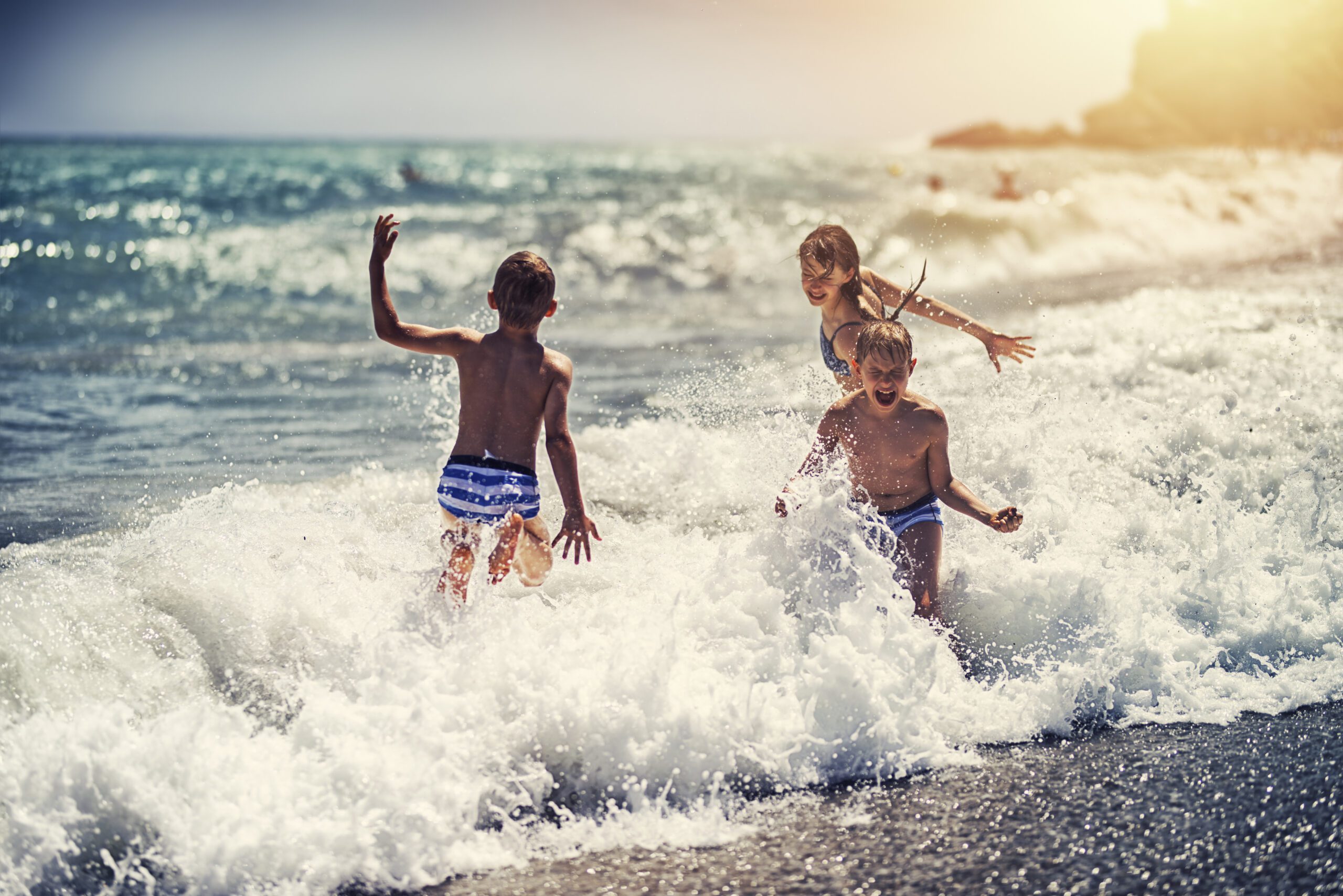 Children enjoying huge waves on beach